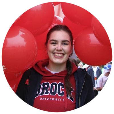 A smiling Brock student surrounded by Brock balloons