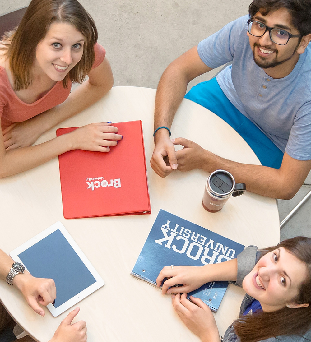 Smiling, studying students around a table. 